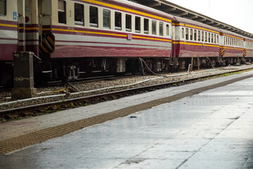 Fototapeta premium Passenger train with maroon and yellow stripes parked at a station platform
