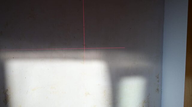 Laser level projecting red lines on wall under construction