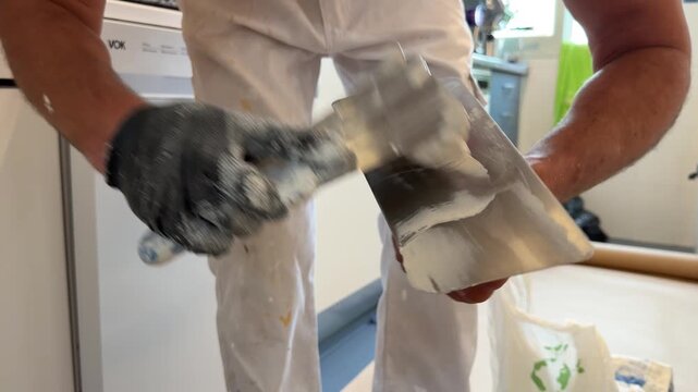 Plasterer preparing white putty with a trowel and spatula