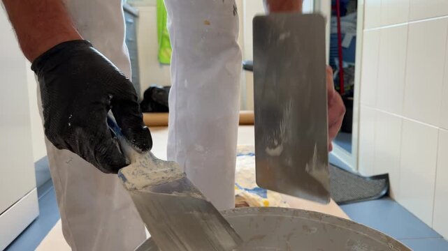Plasterer hands mixing putty with spatulas in a bucket