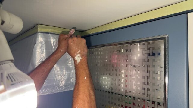Plasterer applying putty on a corner between ceiling and wall at home