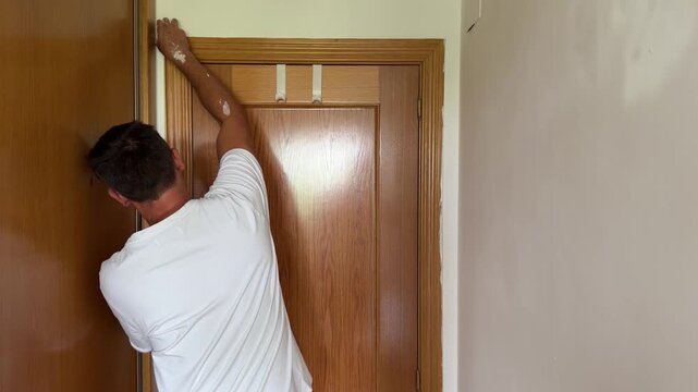 Man applying painter's tape to a door frame before painting