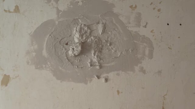 Handyman applying fresh plaster to a damaged wall