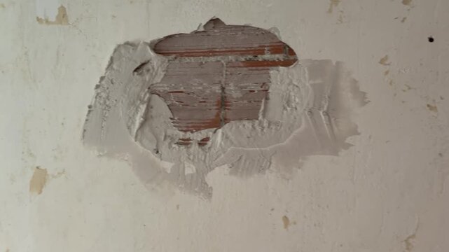 Construction worker plastering a damaged brick wall