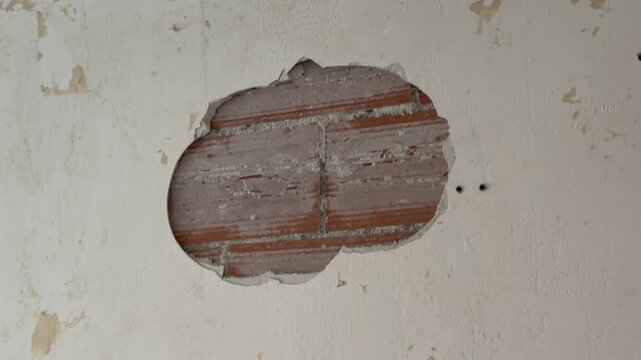 Worker repairs a brick wall with plaster
