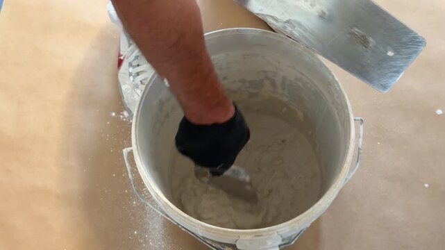 Worker mixing plaster putty in a bucket