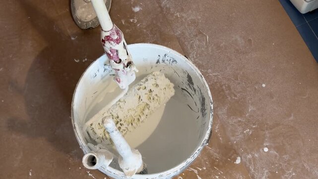 Paint roller dipping into a bucket for home renovation