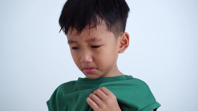 Asian boy crying with tears on his face, looking sad and upset. Upset childhood expression isolated on plain background. Concept for child psychology, parenting, and childhood emotion.