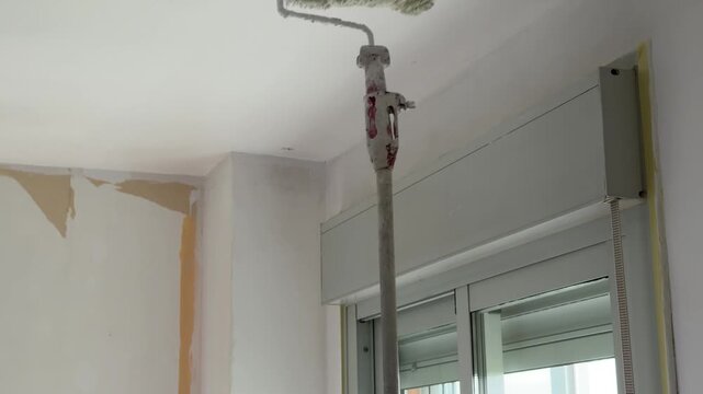 Professional painter applying white paint to a ceiling with a roller