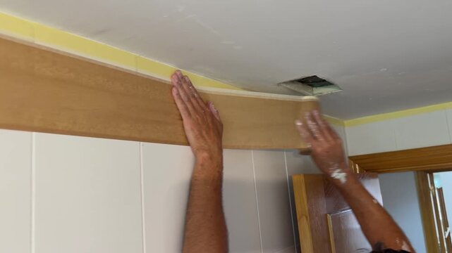 Painter preparing a bathroom for painting with masking tape