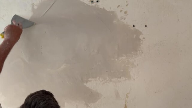 Worker plastering a wall with a spatula