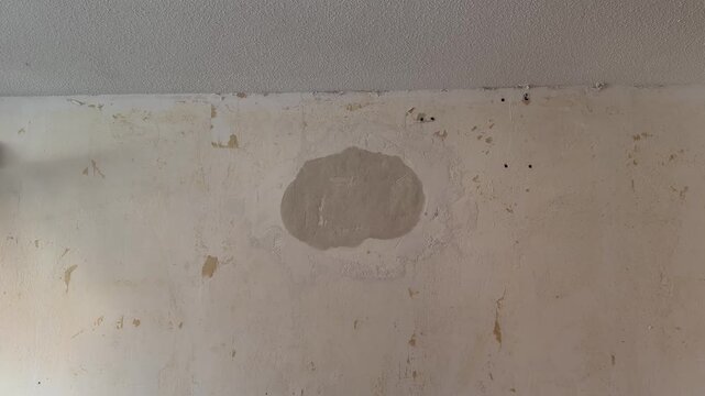 Plasterer applying fresh plaster on an old damaged wall