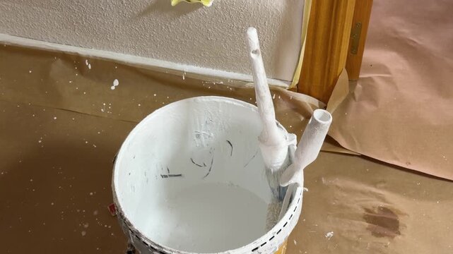 Professional painter dipping a roller in white paint