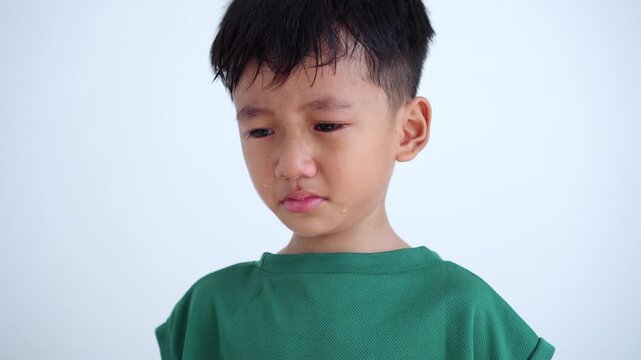 sad Asian boy crying with tears on his cheek, feeling upset, hurt, or disappointed, isolated on a clean white background. Perfect for child psychology and parenting concept.