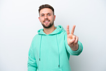 Fototapeta premium Young caucasian man isolated on white background smiling and showing victory sign