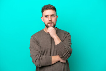 Fototapeta premium Young caucasian man isolated on blue background having doubts and thinking