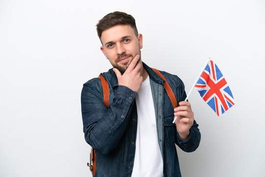 Young caucasian man holding an United Kingdom flag isolated on white background thinking an idea while looking up