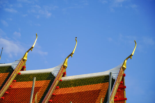 Ornate golden roof details on a traditional Thai temple against a clear blue sky