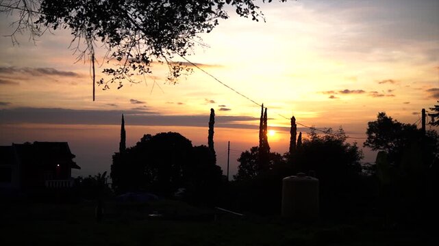 Rural mountain village dramatic sunrise silhouette with cypress trees and vibrant morning sky in 4k video.