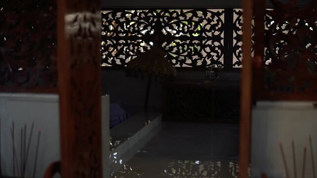 Traditional Javanese room interior with carved wooden screens and incense sticks in 4k video.