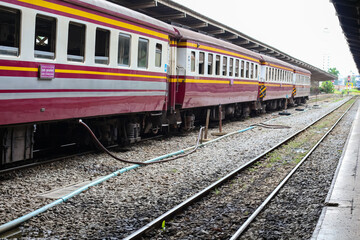 Fototapeta premium Maroon and yellow train cars parked at a station with multiple tracks