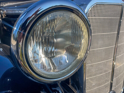 Vintage classic car headlight with chrome trim and radiator grill for automotive restoration website design. Retro vehicle headlight close-up background for luxury car rental and exhibition mockups