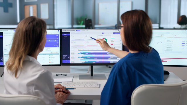 Woman In Medical Uniform Studies Patient Data On Computer