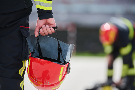 Firefighter Holding Red Helmet Outside Station During Emergency Response And Team Training Exercise