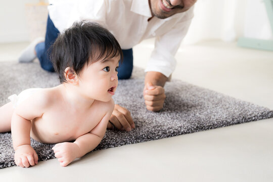 ハイハイする赤ちゃんを見守る父親 育児・子育て・成長・親子のふれあいのイクメン育休パパと赤ちゃんのイメージのクローズアップ