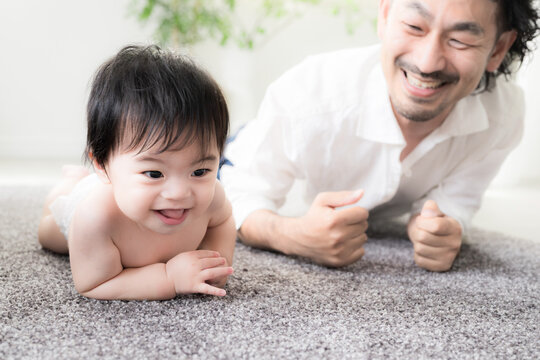 ハイハイする赤ちゃんを見守る父親 育児・子育て・成長・親子のふれあいのイクメン育休パパと赤ちゃんのイメージのクローズアップ