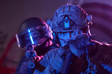 Obraz premium Tactical Soldiers Team in Camouflage Gear Aiming Rifles During Night Urban Operation With Helmet Visors