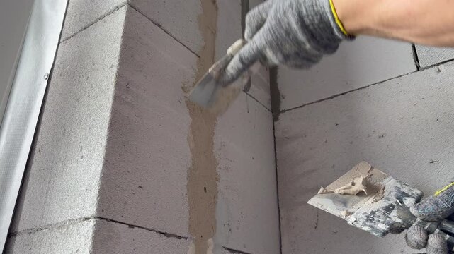a construction worker applying mortar to aerated concrete blocks with a trowel