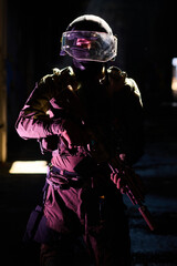 Obraz premium Tactical Soldier in Ballistic Helmet and Visor Holding Rifle in Dark Urban Environment