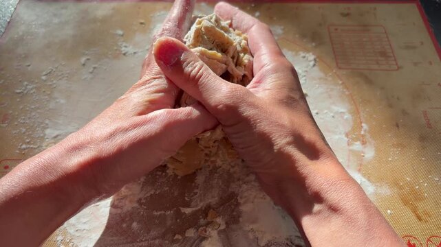 hands kneading cookie or cake dough in bright sunlight. Homemade baking