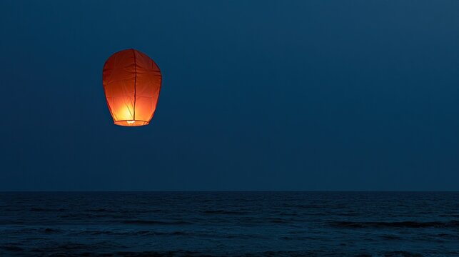 Glowing lantern floats over dark ocean under twilight sky