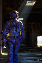 Obraz premium Armed Soldier in Camouflage Tactical Gear Walking Through Dim Urban Ruins With Dramatic Light