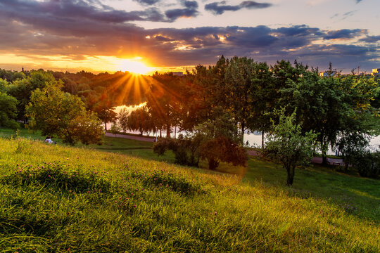 Dramatic sunset with sun rays over a lake and wildflower meadow in Tineretului Park in Bucharest.