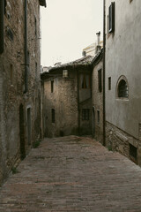 Fototapeta premium Historic Medieval Stone Street in Italian Old Town, Narrow Cobblestone Alley with Rustic Architecture, Atmospheric European Urban Heritage and Timeless Historic Passage