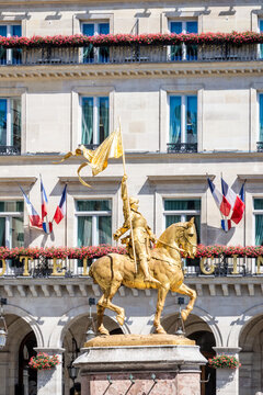 Paris, France - June 17, 2026: Side view of the gilded bronze equestrian statue of Joan of Arc by Emmanuel Fremiet, erected in the Pyramides square in 1874, with French flags in the background.