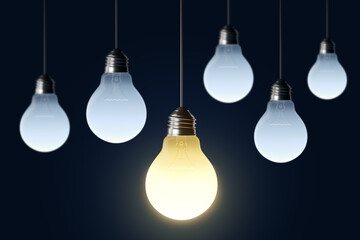 Glowing light bulbs hanging against a dark background, with one bright bulb symbolizing creative ideas, innovation, and inspiration. 3D Rendering © Who is Danny