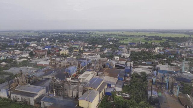 Drone shot with a smooth right-to-left curved movement across an industrial zone in Khajanagar, Kushtia, featuring factories, rooftops, infrastructure, and the rural environment around the area.