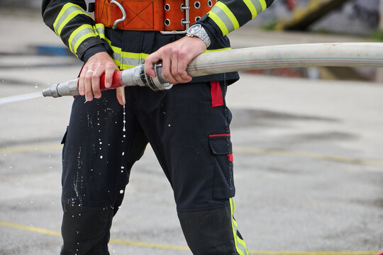 Firefighter Holding Water Hose During Training Or Emergency Response, Close-Up On Hands And Uniform