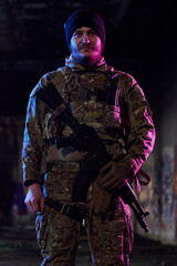 Obraz premium Armed Soldier in Camouflage Tactical Gear Holding Rifle in Urban Night Environment