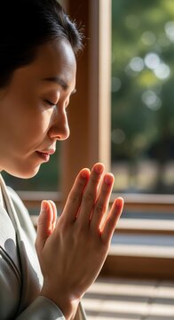 Close Up Profile Of Japanese Woman Praying Peacefully Inside Wooden Temple Near Window