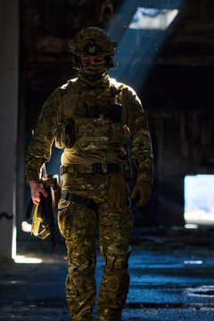 Tactical Soldier in Camouflage Gear With Rifle Walking Through Abandoned Urban Building Bathed in Light