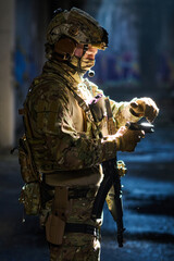 Obraz premium Tactical Soldier In Camouflage Gear Preparing Handgun During Night Operation With Rifle and Helmet