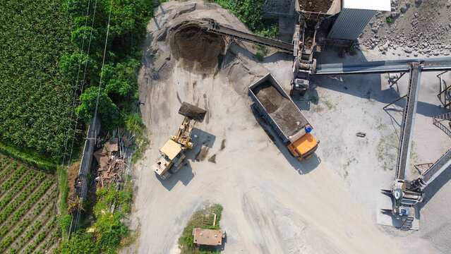 Aerial top view of wheel loader loading dump truck with sand and gravel at aggregate processing plant