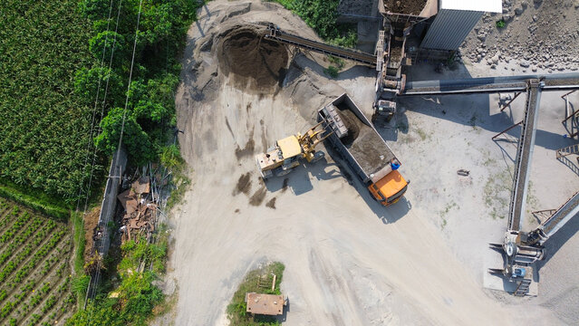 Aerial top view of wheel loader loading dump truck with sand and gravel at aggregate processing plant