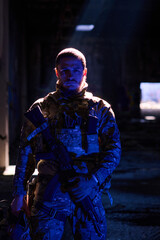 Obraz premium Tactical Soldier In Camouflage Gear Holding Rifle Under Dramatic Night Light In Urban Ruins