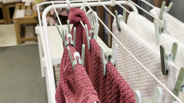 Bath towels and laundry hanging on a drying rack with clothespins in a home interior